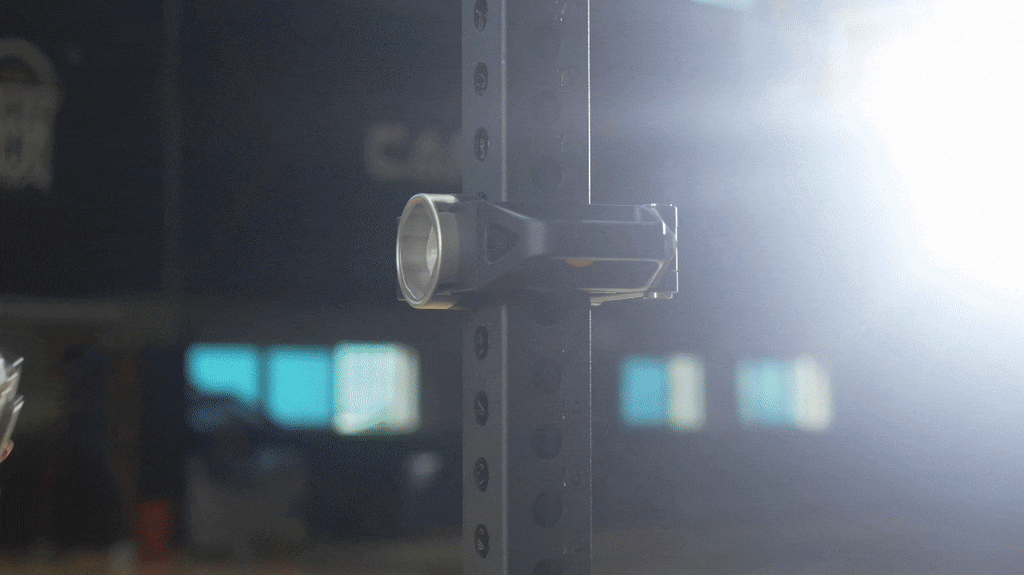 A trainer adjusting the VOLTRA I across a squat rack.
